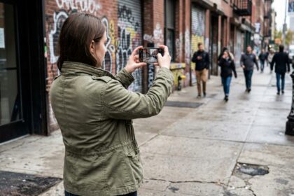 Jeune femme filmant une scène urbaine avec son smartphone avant d'intégrer une école de cinéma